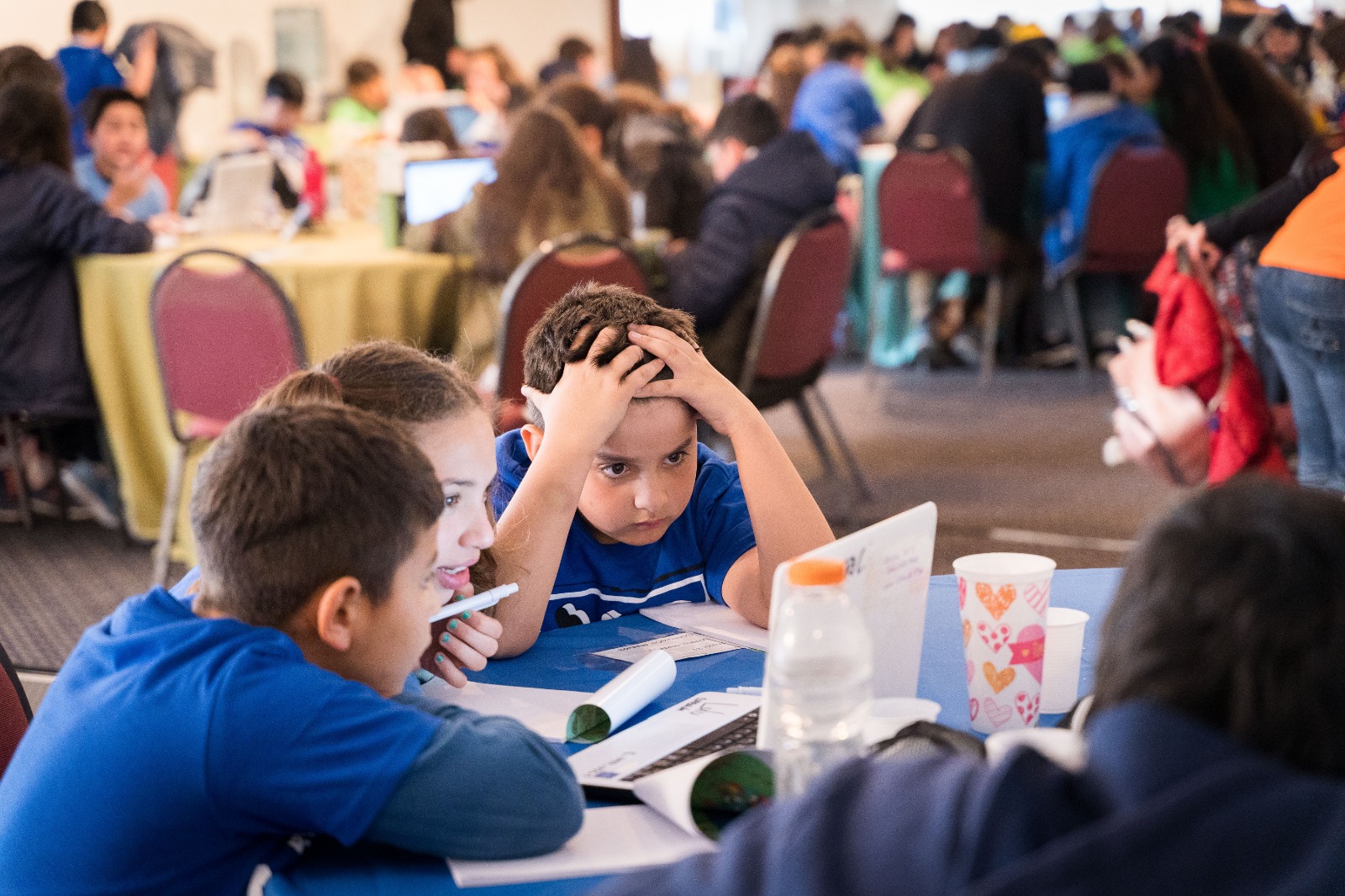 Niños pequeños pensando cómo resolver un problema frente a la computadora durante un encuentro presencial de encuentro matemático 2019