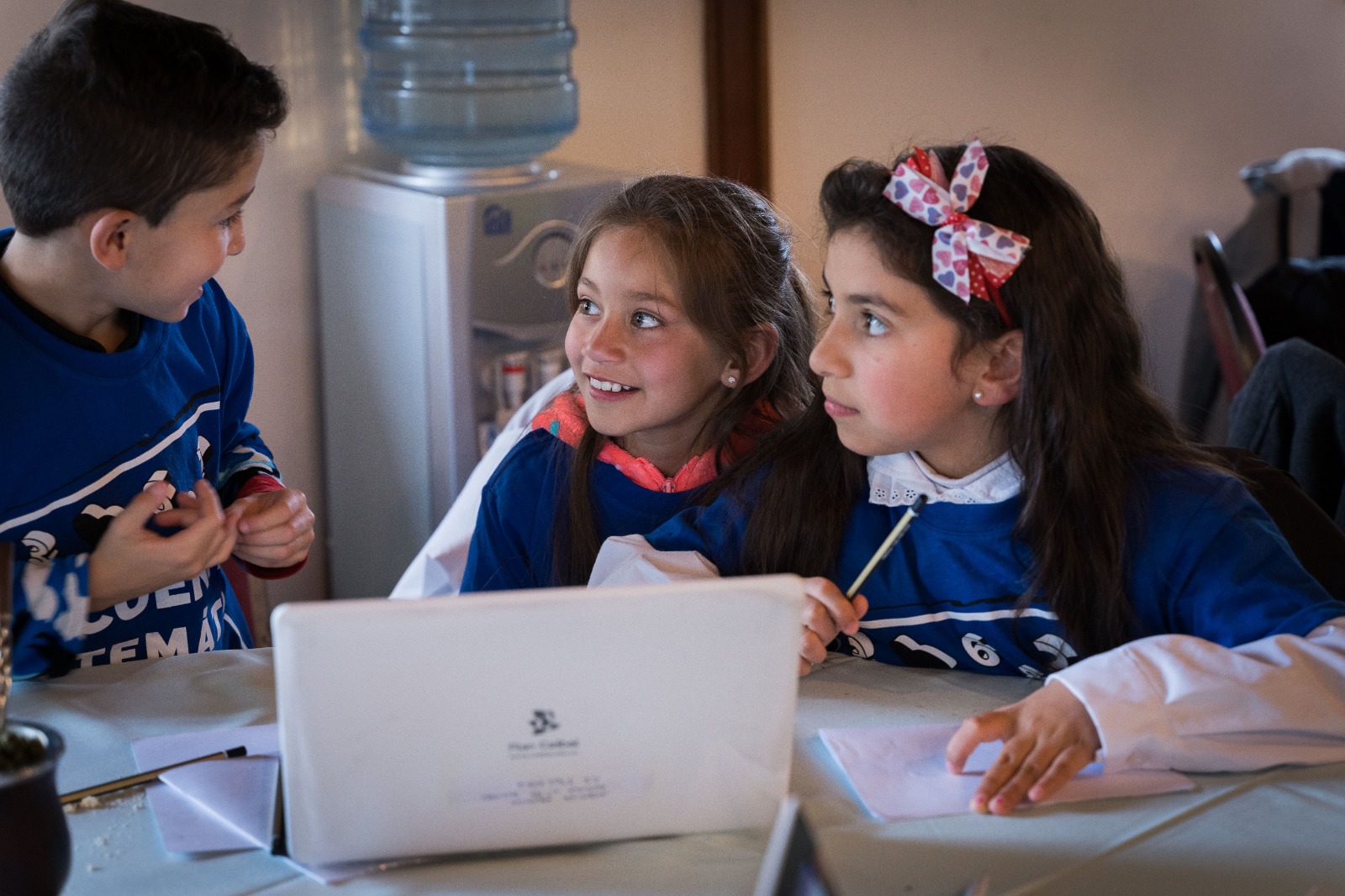 un niño y dos niñas frente a una computadora en el encuentro matemático 2019